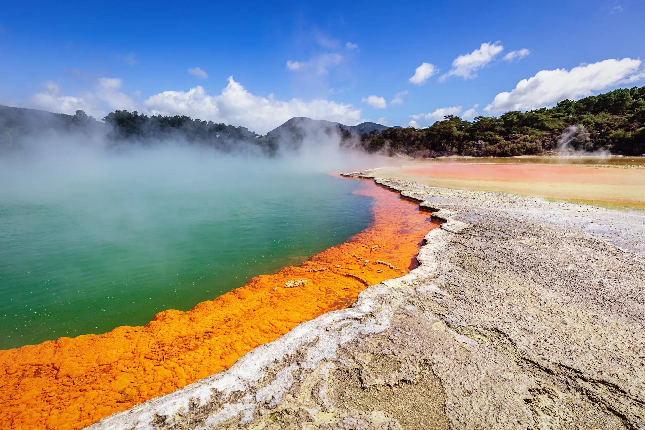 Colorful orange - green Champagne Pool in the Waiotapu Thermal Wonderland. The pool is a 65 m wide spring, containing multiple minerals that are presently depositing in the surrounding sinter ledge. Waiotapu, North Island, New Zealand.
