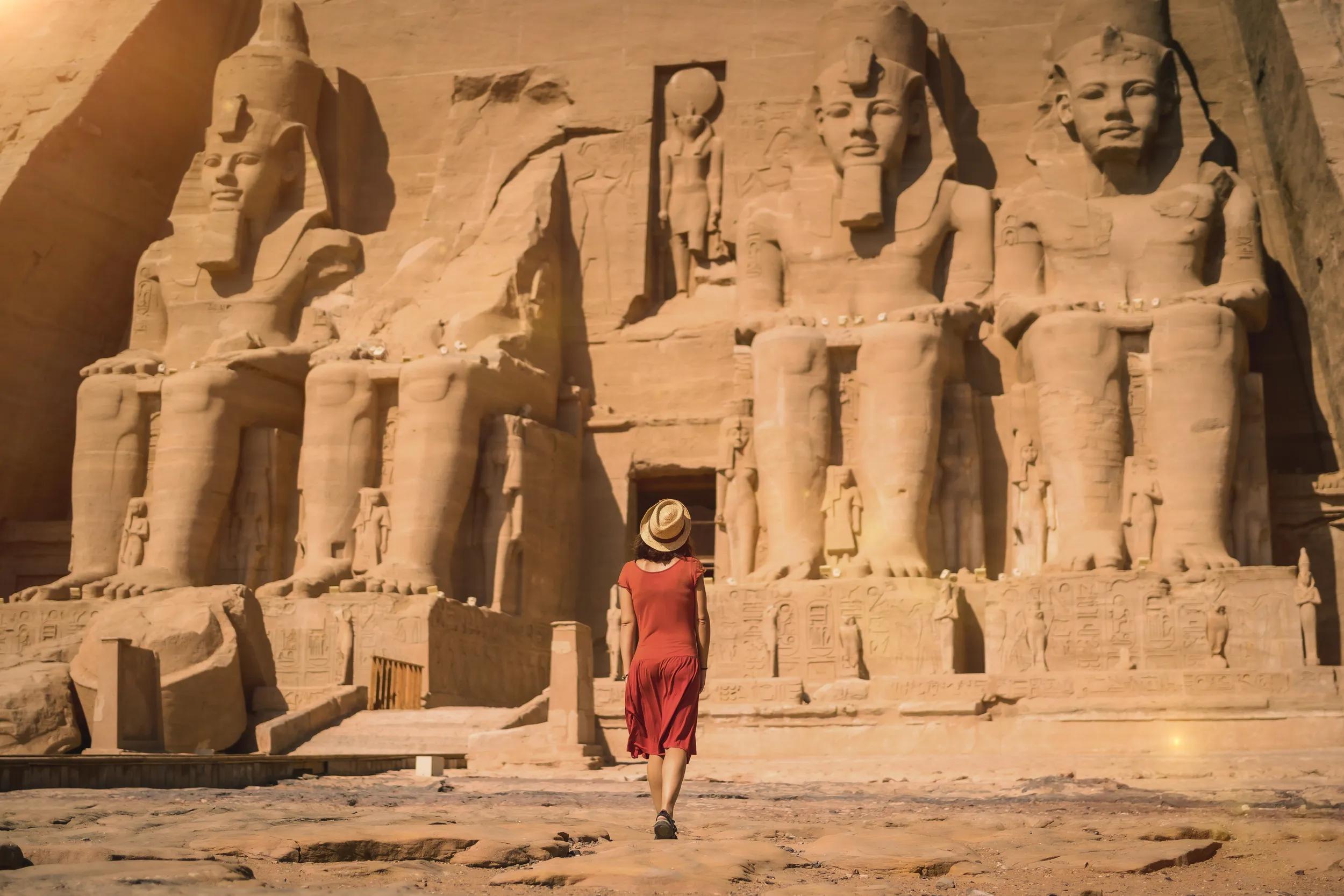 A young tourist in a red dress entering the Abu Simbel Temple in southern Egypt in Nubia next to Lake Nasser. Temple of Pharaoh Ramses II