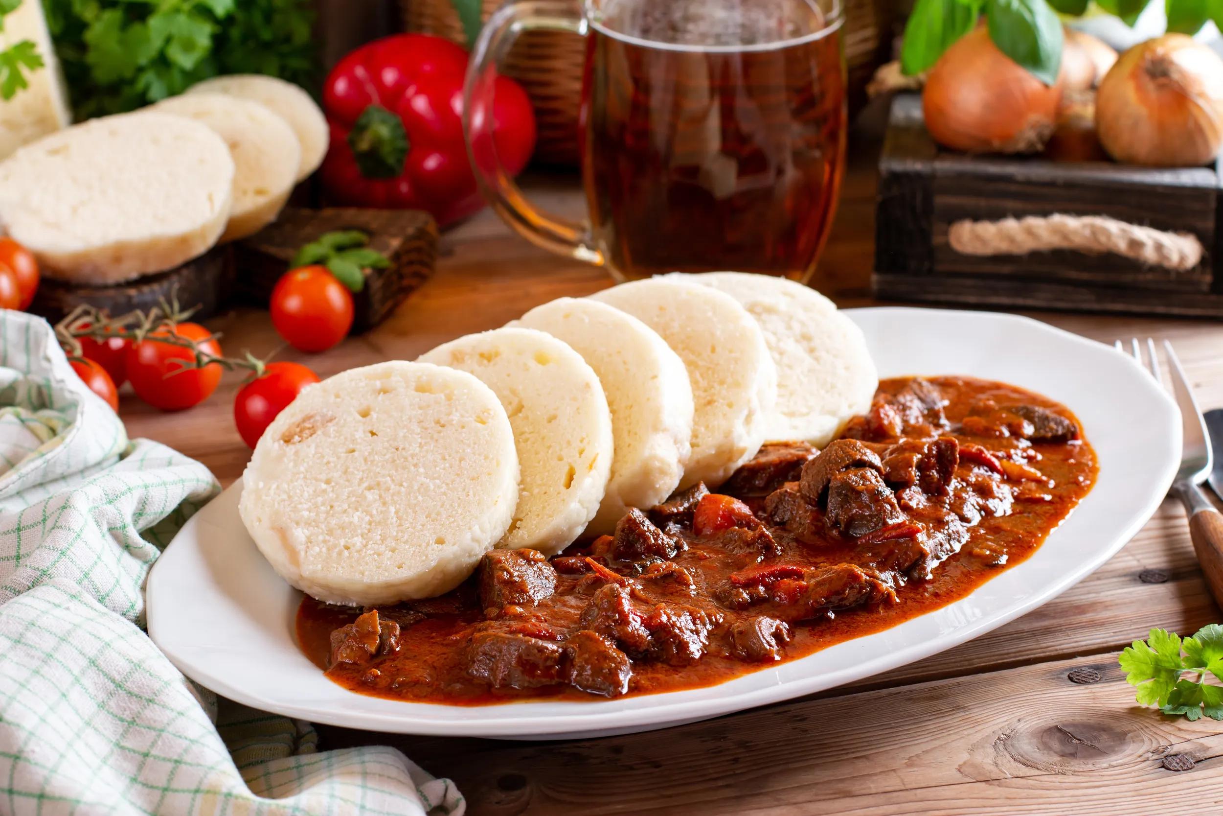 Beef goulash and dumplings (knedliky) on white plate from Czech Republic. Hungarian traditional meal. Traditional Czech dish