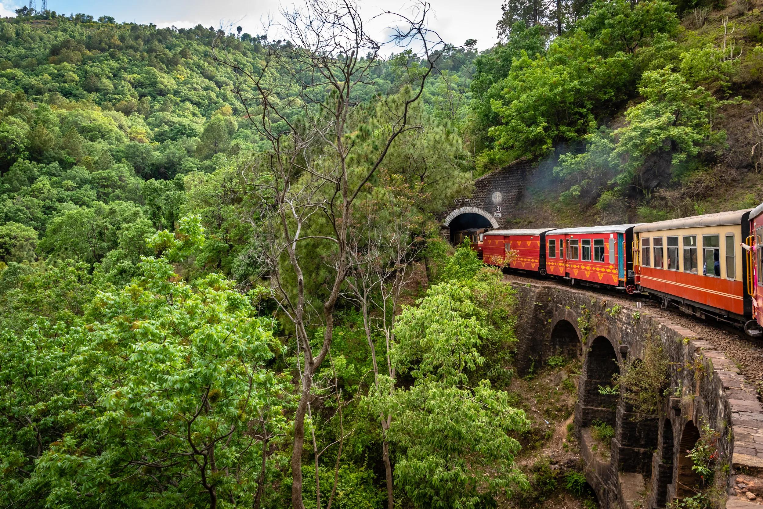 View from moving train on arch bridge over mountain slopes, beautiful view, one side mountain, one side valley. Toy train from Shimla to Kalka in Himachal Pradesh, India