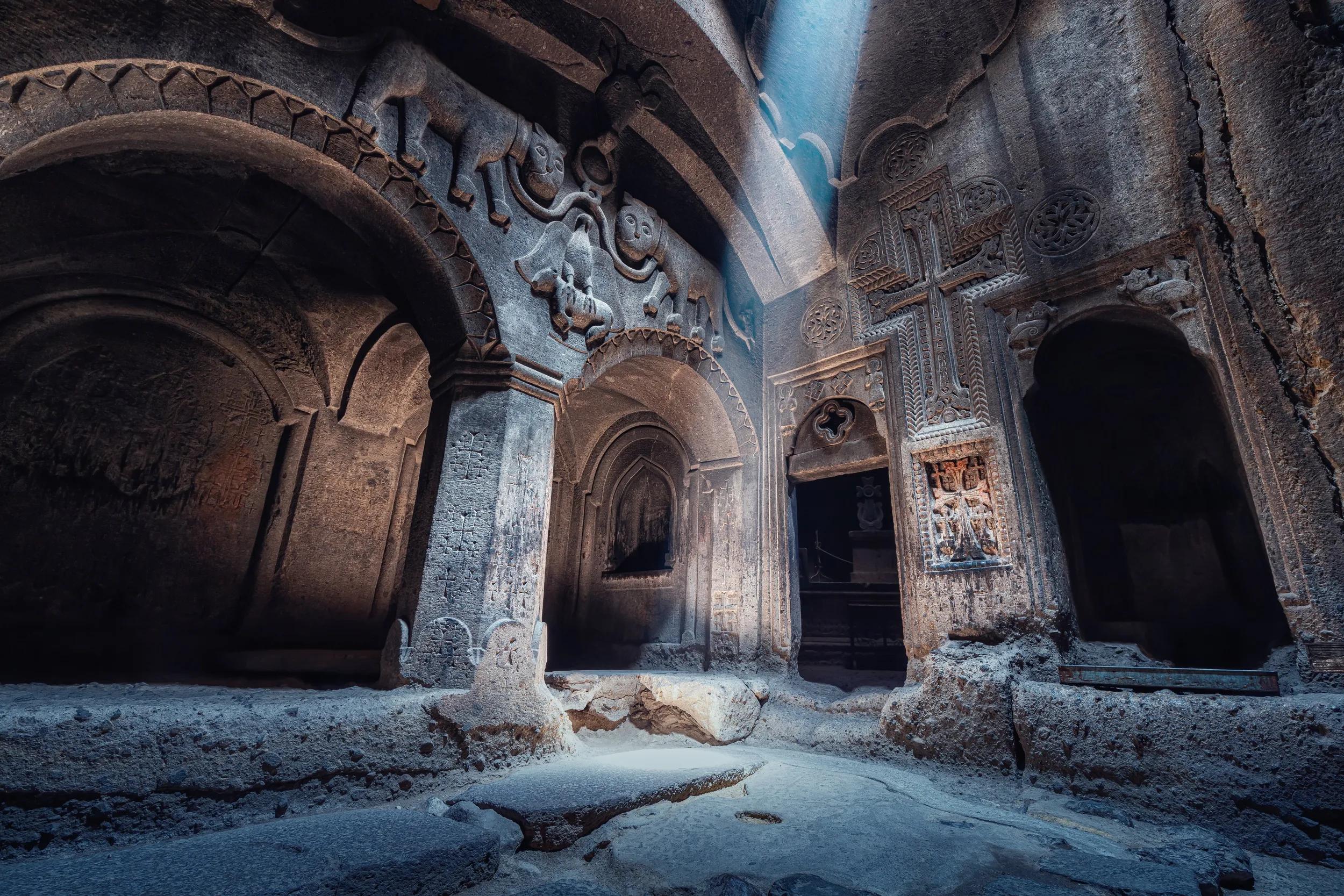 Interior of the famous Geghard Monastery and church carved into the rock. A ray of light illuminates an ancient bas-relief depicting lions in the hall