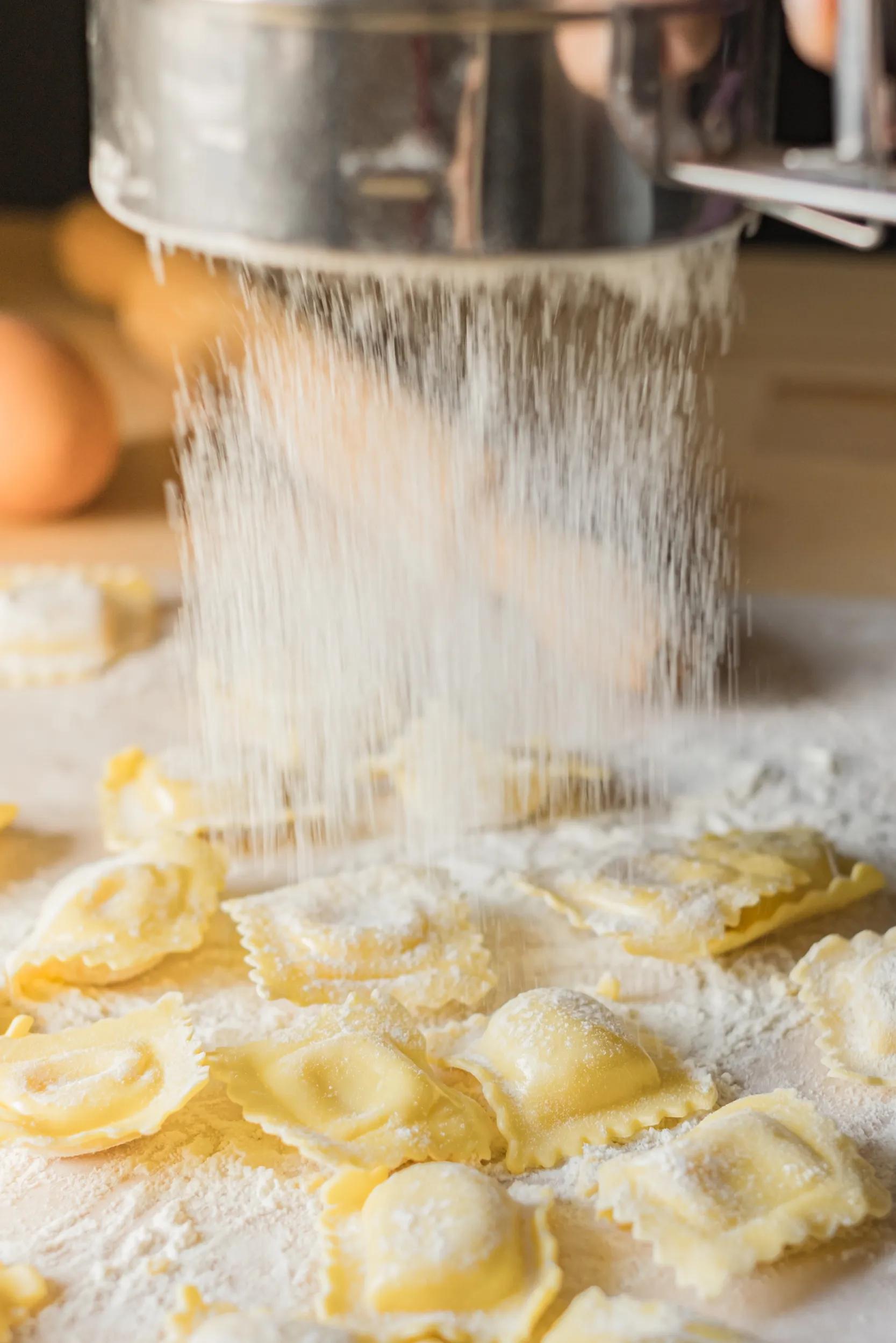 Fresh ravioli pasta is sprinkled with flour. Vertical image.