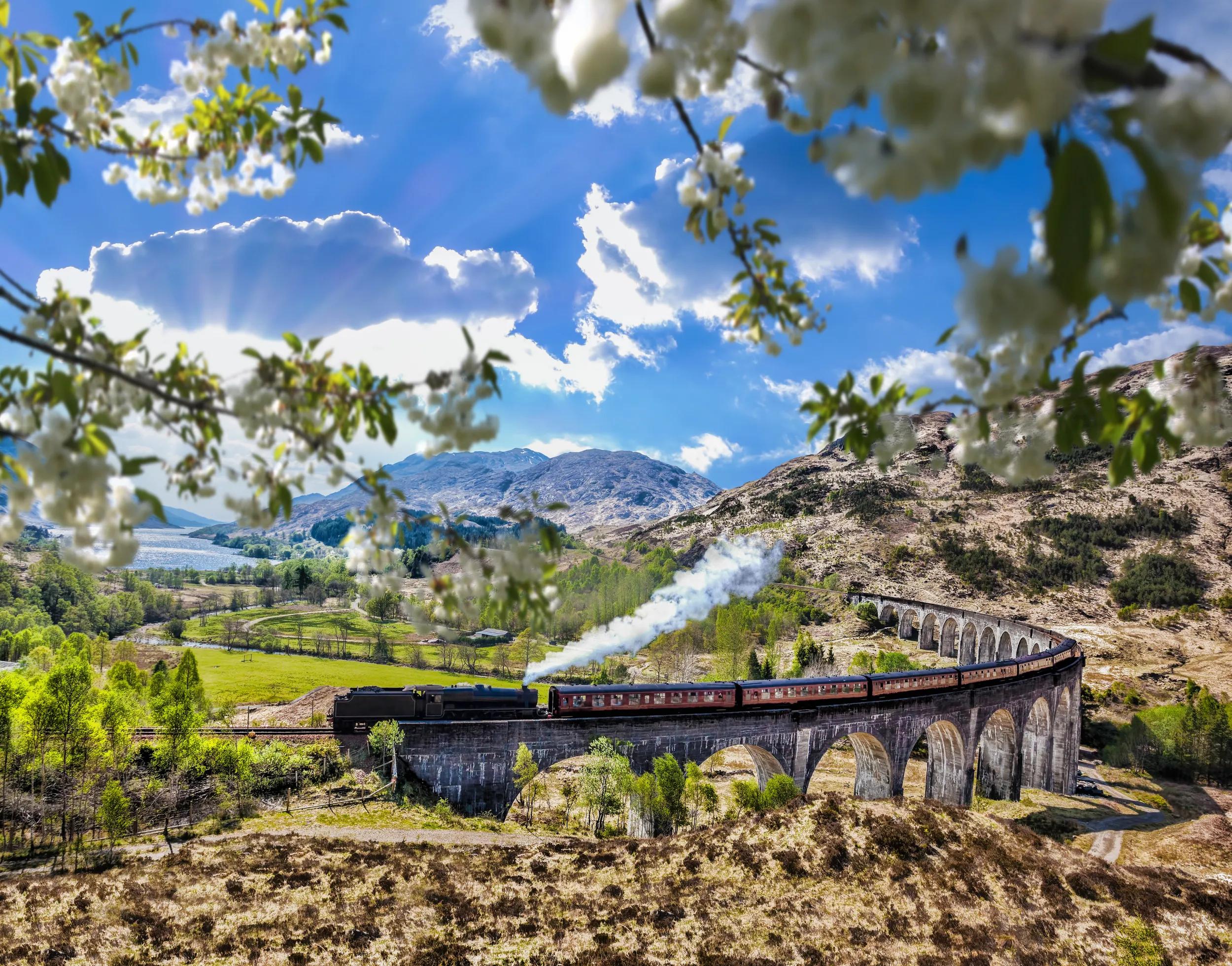 Glenfinnan Railway Viaduct in Scotland with the Jacobite steam train against sunset over lake