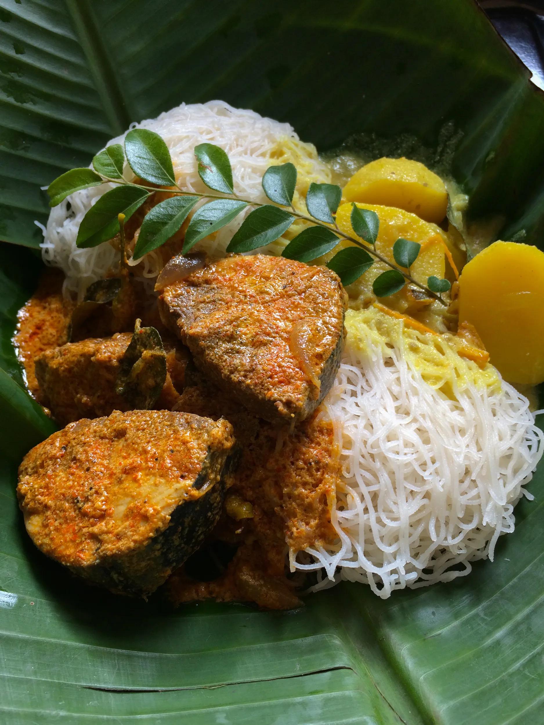 Most popular Sri Lankan breakfast or dinner food menu . String hoppers with white potato curry and spicy fish curry traditionally served on a banana leaf .